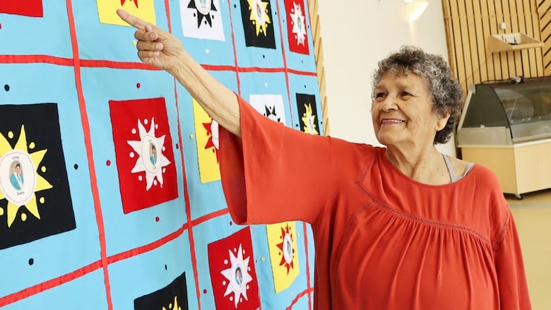 Wagmatcook Elder Nancy (Nano) Bernard points to her first ever graduation quilt that she started in 1992. Over the past 33 years, Bernard has featured more than 200 people on her quilts as a way of honouring Wagmatcook's school graduates.