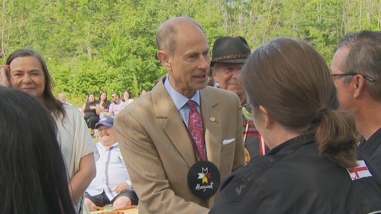 A person shakes hands with another people as people standing nearby look on.