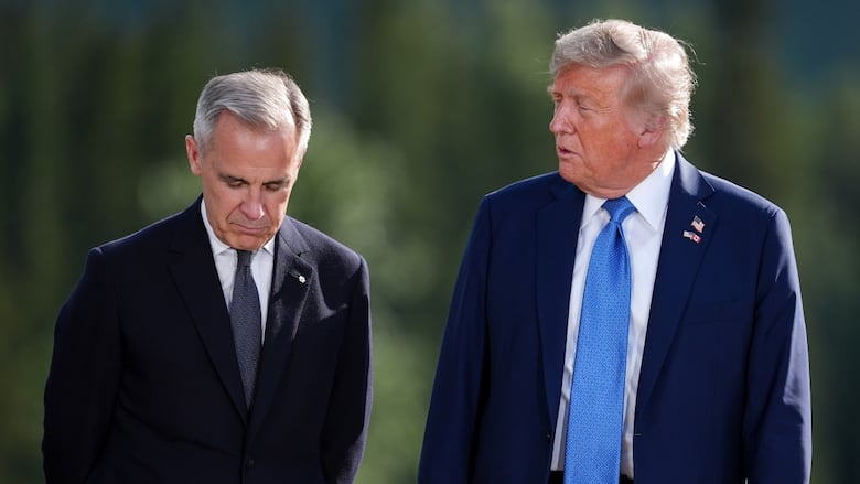 Two men in suits stand side by side. One is looking at the other, whose eyes are downcast.