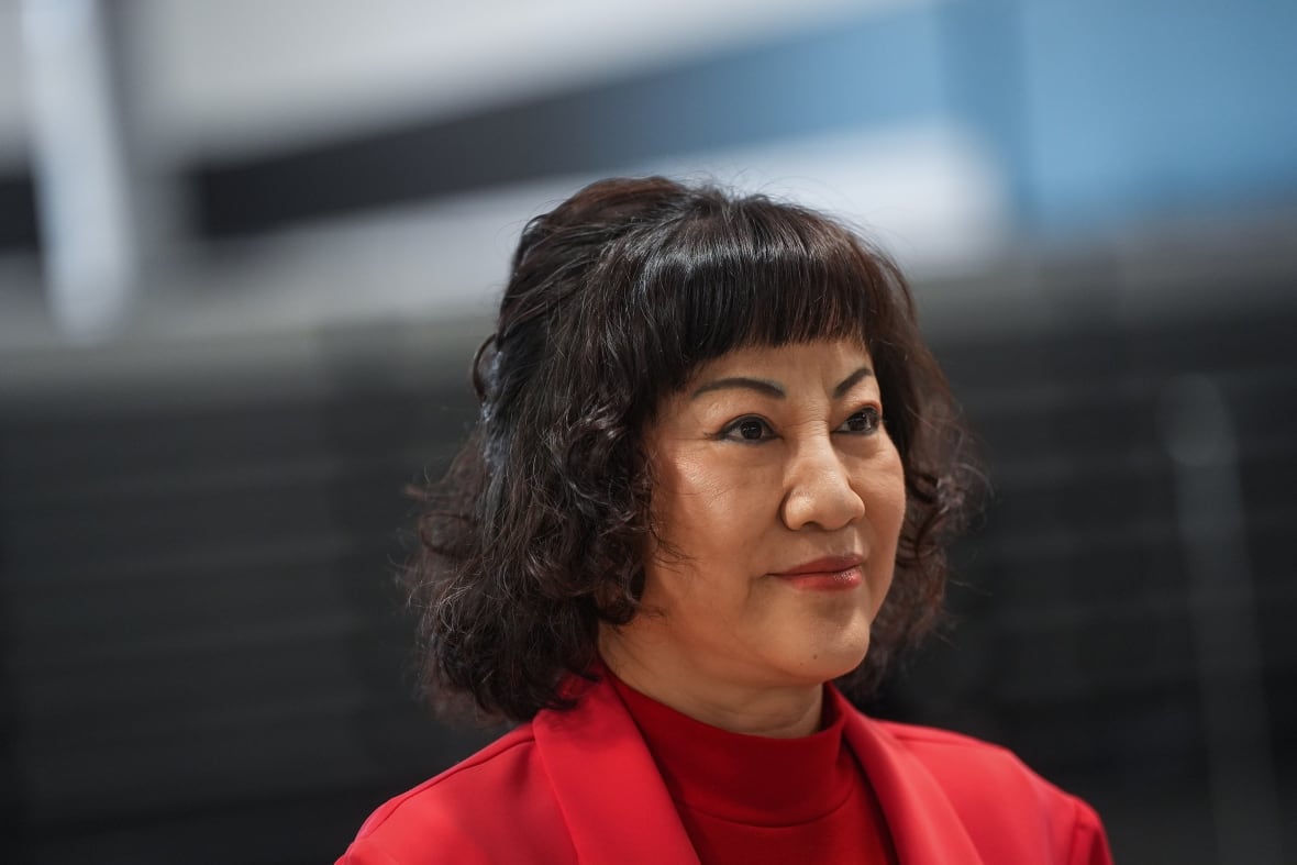 Mujer de Asia Oriental con un corte de pelo oscuro y lápiz labial rojo, con tapa roja y blazer rojo a juego.