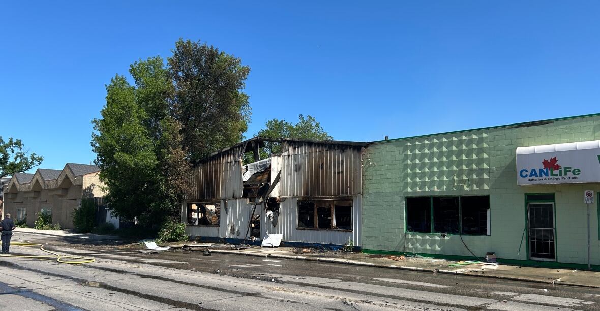 A white and green building with fire damage is seen. 