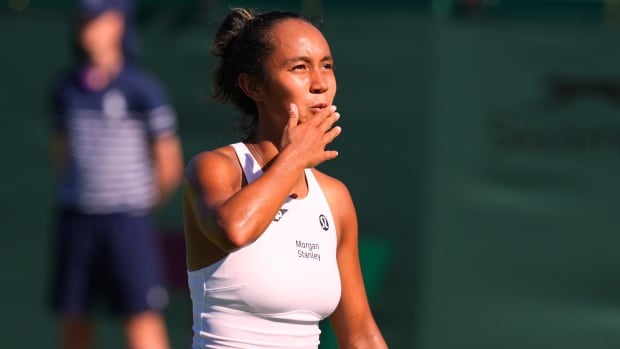 A female tennis player blows a kiss to spectators.