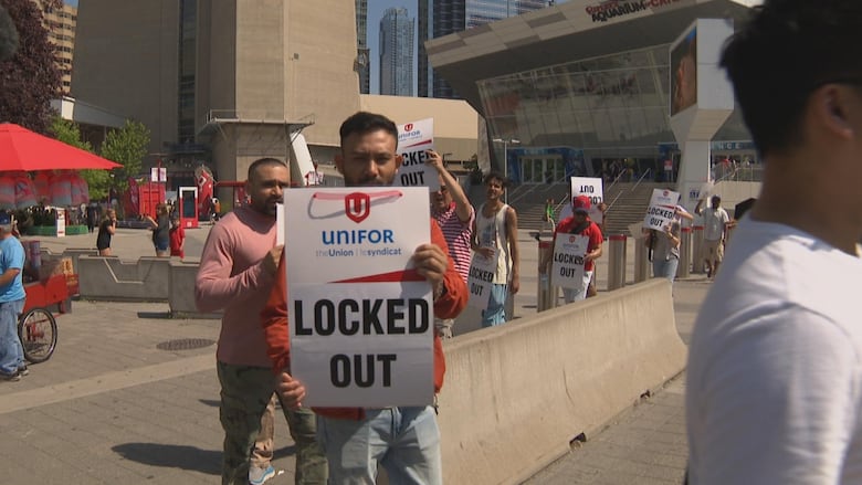 man holding a sign that reads "locked out."