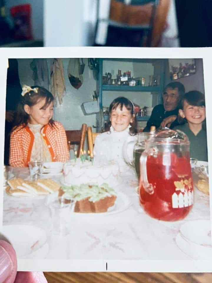 Children sit at a table with cake and juice in what appears to be a birthday party.
