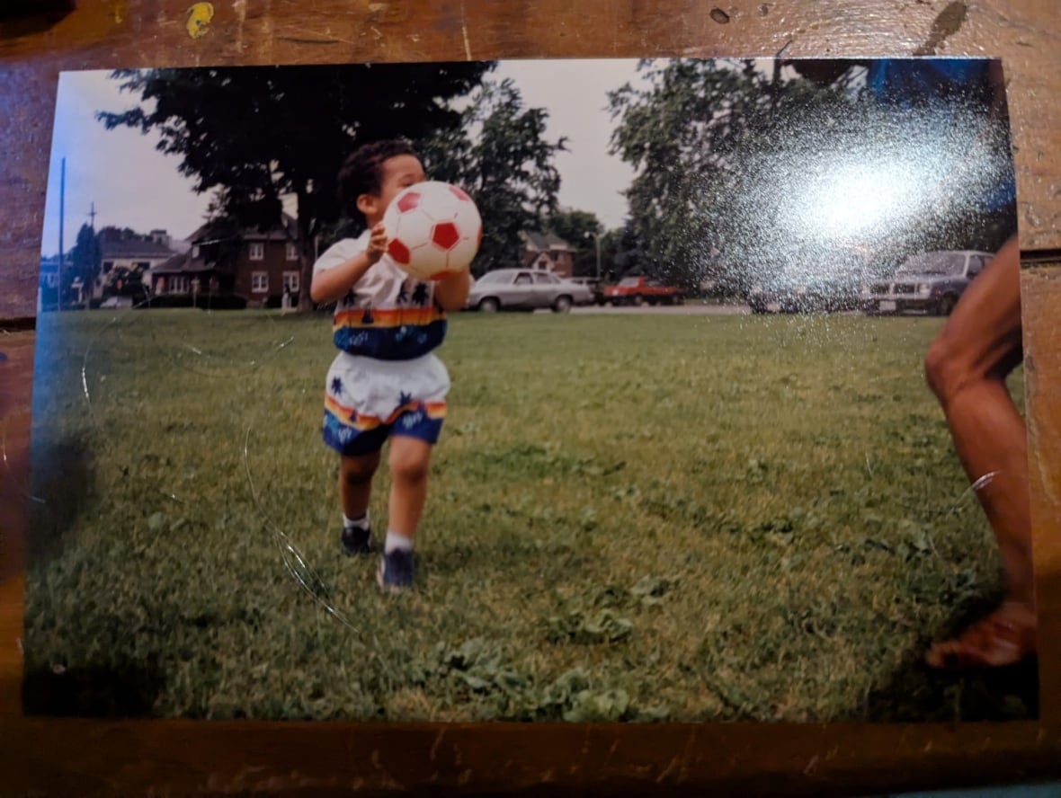 An old photo of a small boy holding a soccer ball.