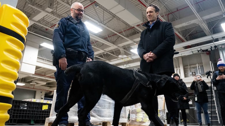 Canada's fentanyl czar Kevin Brosseau, right, is seen with Denver, a Canada Border Services Agency narcotics detection dog, during a tour of the CBSA Lansdowne port of entry in Lansdowne, Ont., on Wednesday, Feb. 12, 2025.