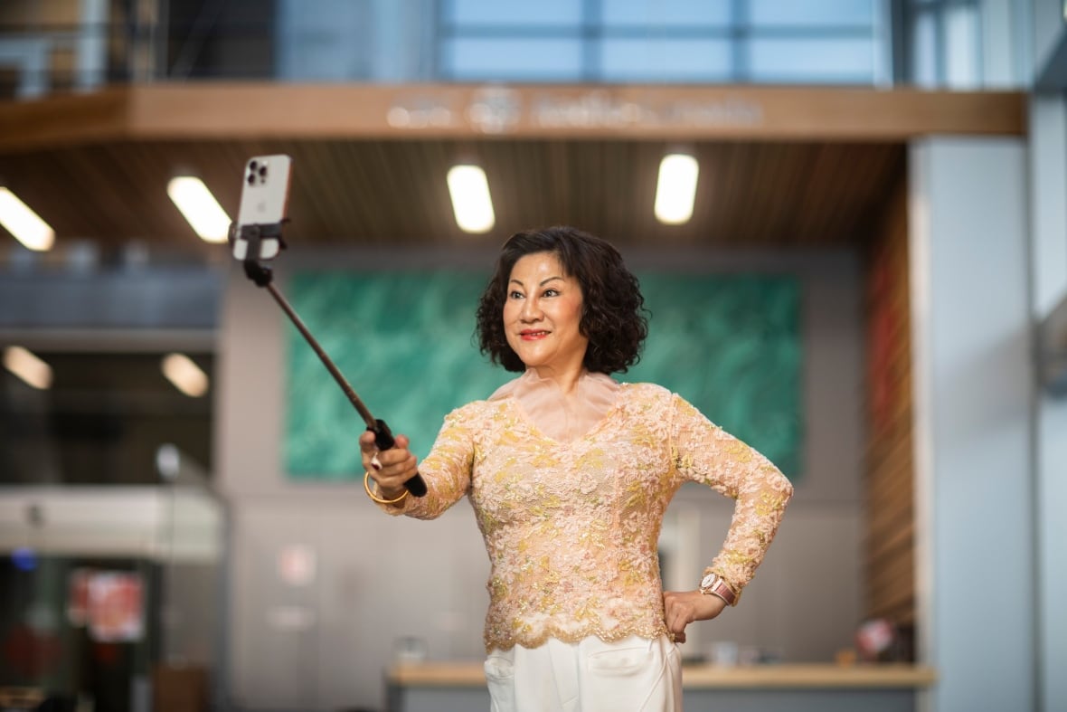La mujer del este de Asia tiene un palo selfie antes de la obra de arte azul.
