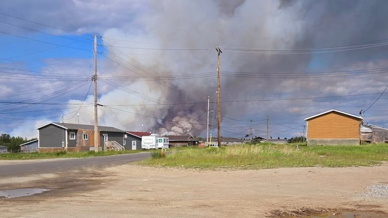 Smoke beyond a few buildings on a dirt road