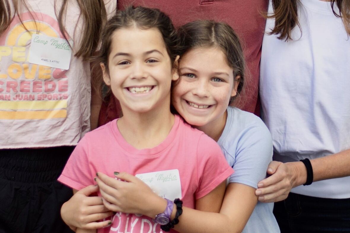 Two children embrace and smile while posing for a photograph.