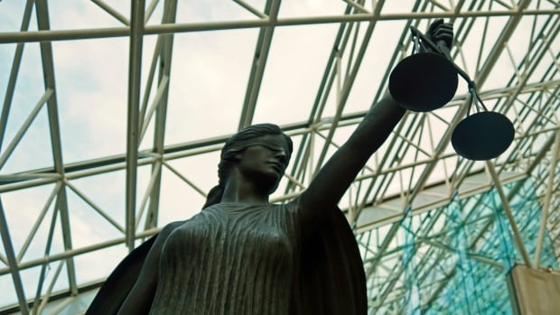 A statue of a blindfolded female figure holding a scale inside a glass-roofed building
