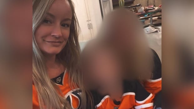 A blond woman smiles next to two children whose faces are blurred.