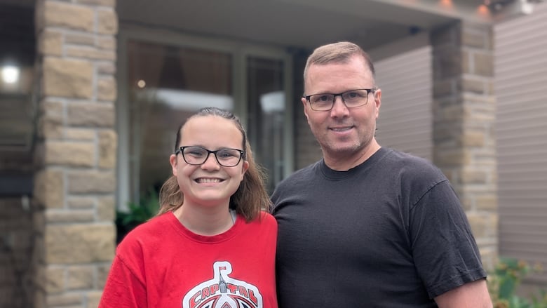 A man wearing a black shirt and a girl wearing a red shirt that reads Capital City Condors