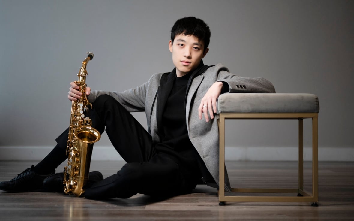 Jason Xu reclines on the floor with his saxophone.