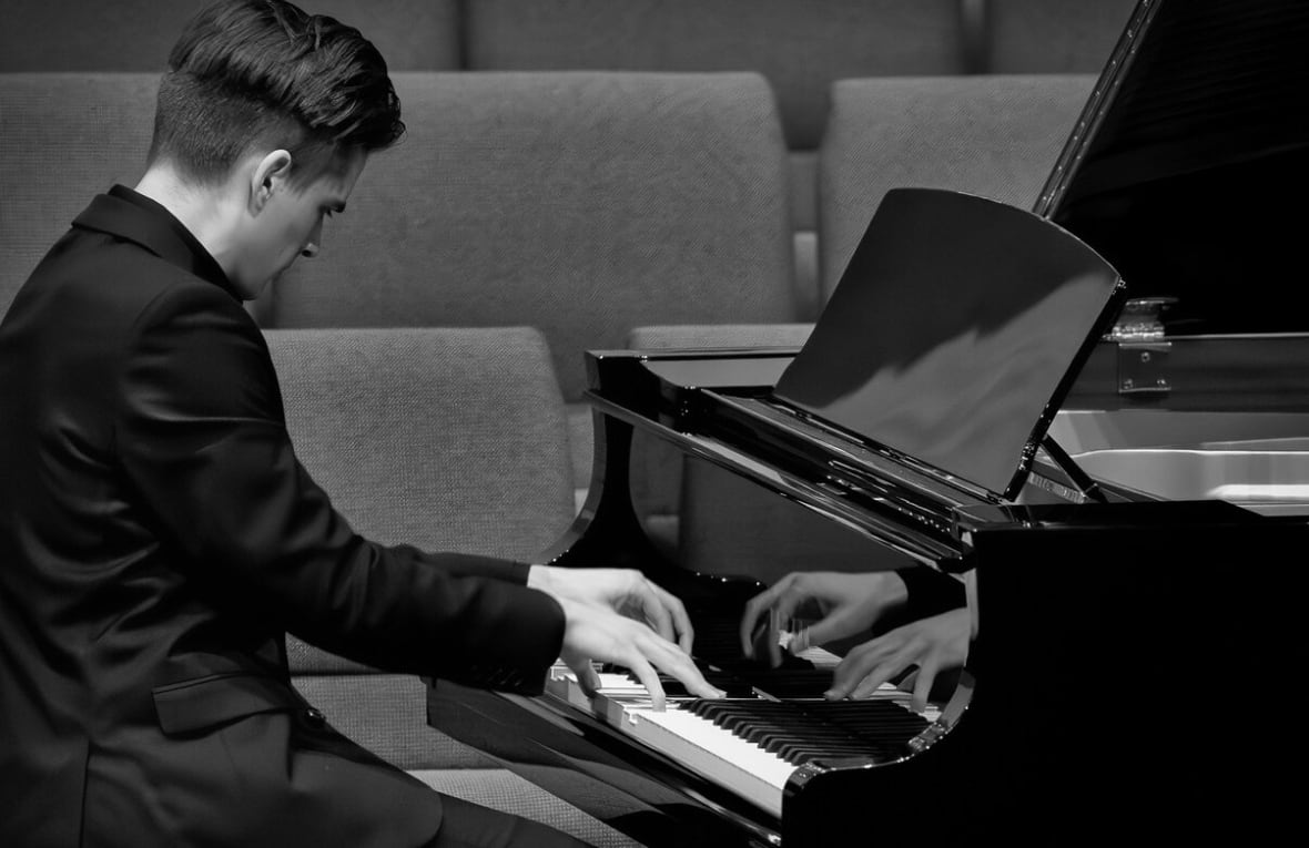Ari Hooker plays a concert grand piano.