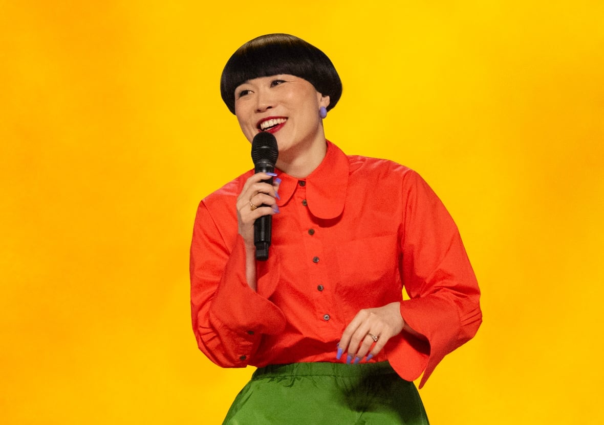 A smiling woman speaks of microphone.