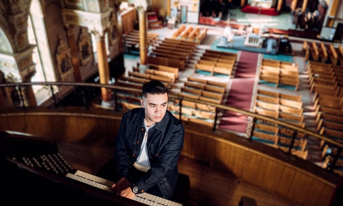 Alexander Straus-Fausto is pictured in the organ loft of a large, historic church.