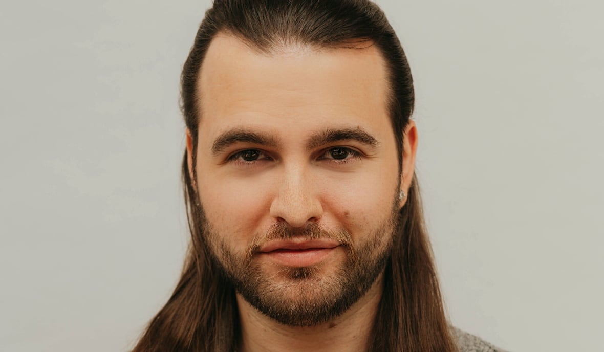 Bass-baritone Alex Halliday faces the camera, with his long hair and beard.