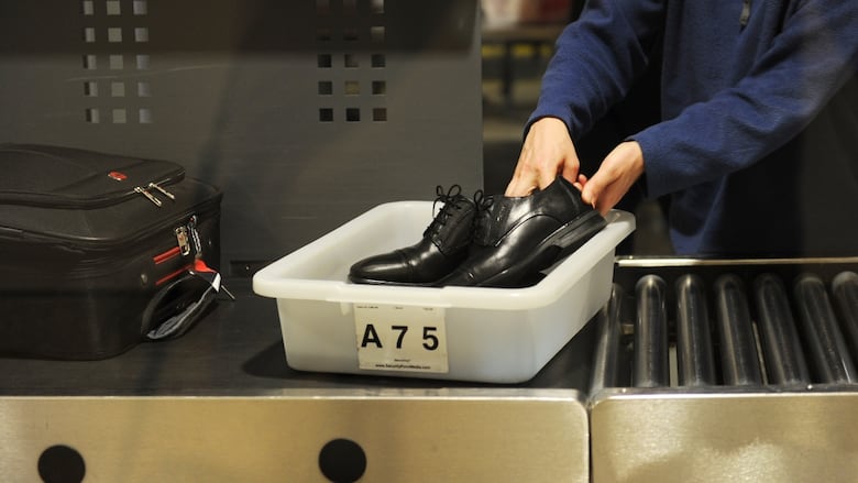 An air traveler places his shoes in a bin before a security check at Los Angeles International Airport.