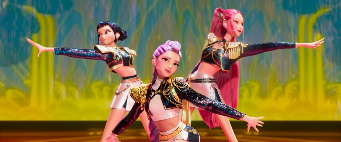Animated screengrab of three girls in shiny outfits and colourful hair performing a song onstage.