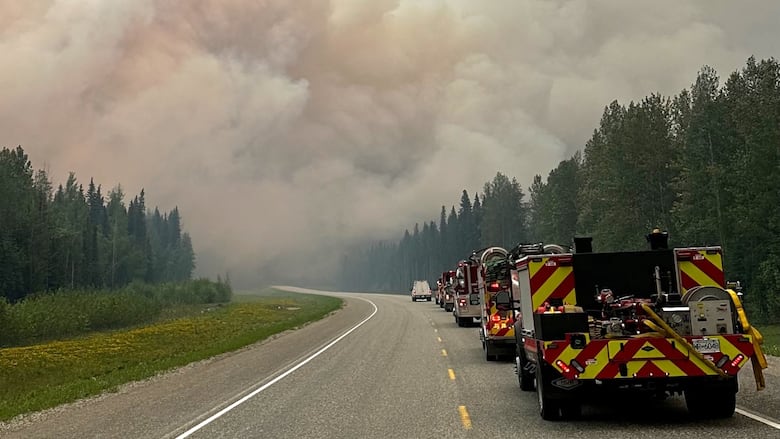 Smoke rises as firetrucks head to a wildfire site.