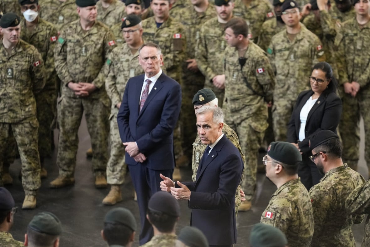 Two men in suits are seen with soldiers standing around them.