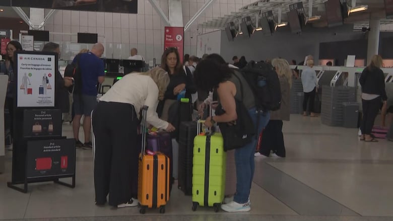 Passengers are hover over their suitcases at the airport.
