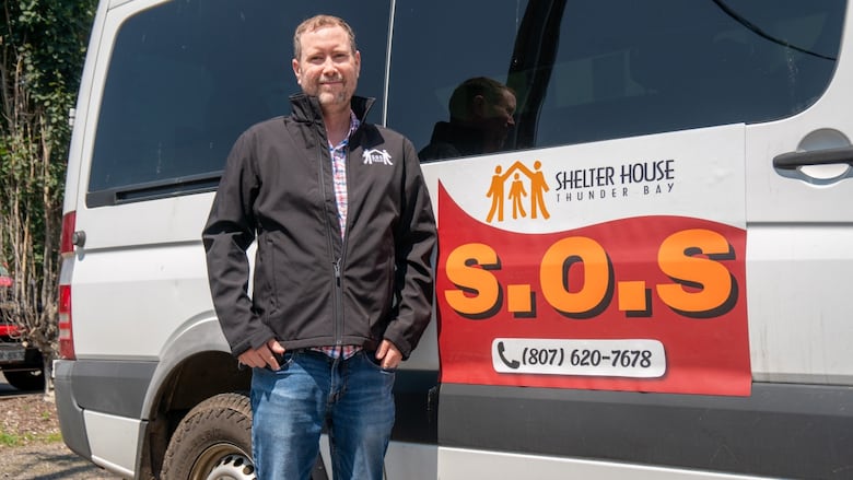 A person is seen standing next to a white van, which says "Shelter House Thunder Bay S.O.S."