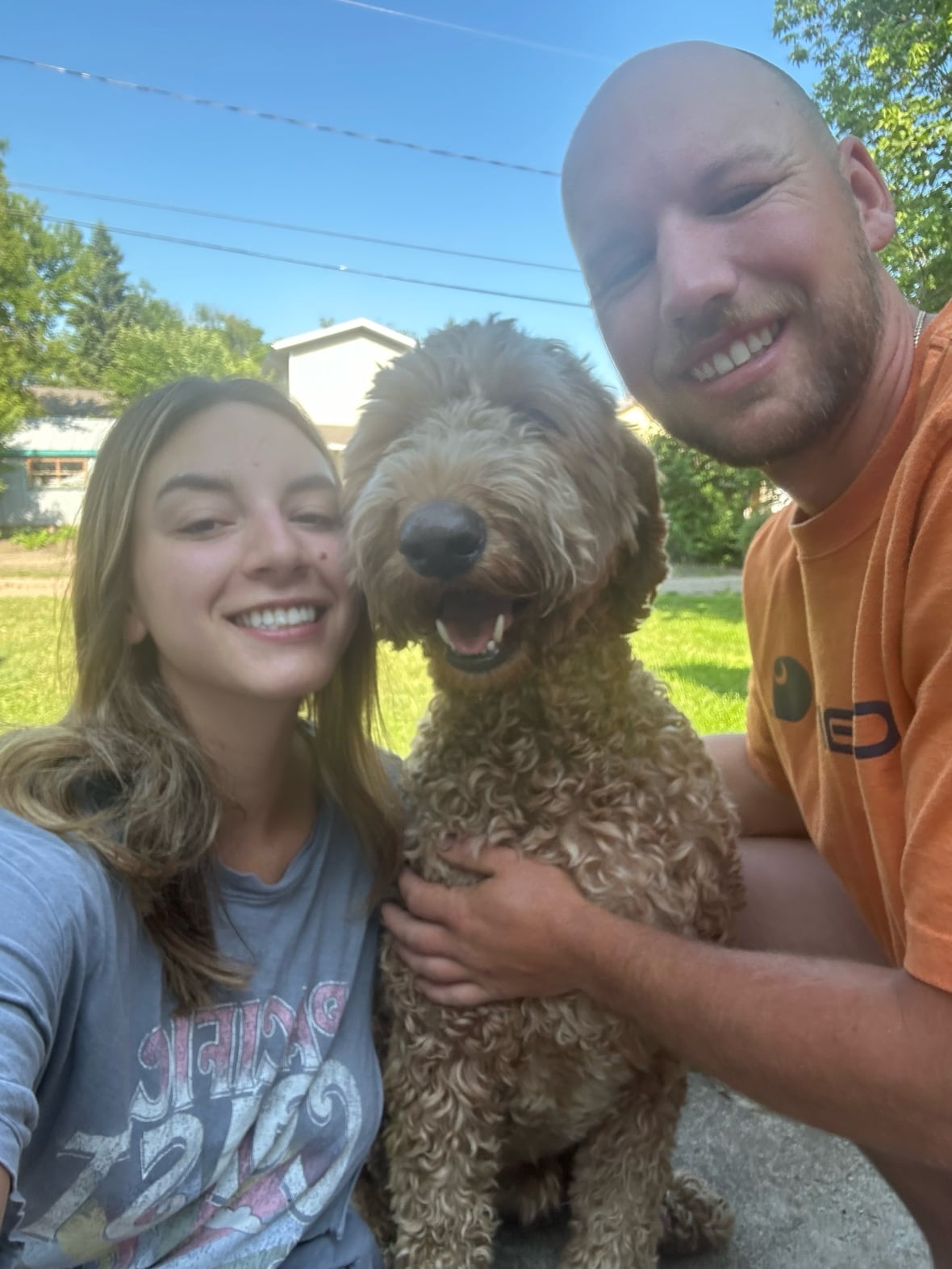 A picture of a couple and their dog taking a picture together.