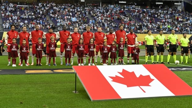 A soccer team stands in front of its flag.
