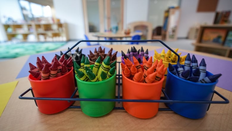 Crayons on top of a table in a classroom.