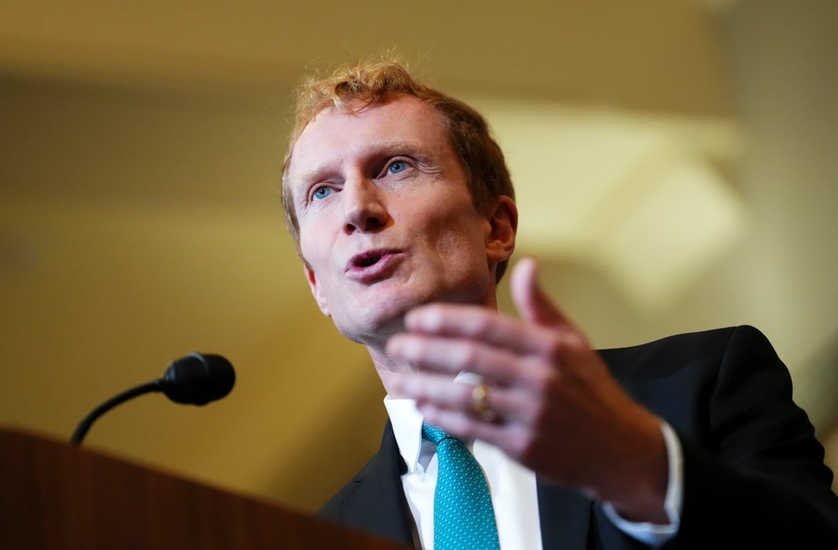 Man in a black suit standing in front of a microphone