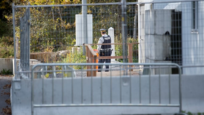 A police officer stands behind a gate at a former border crossing.