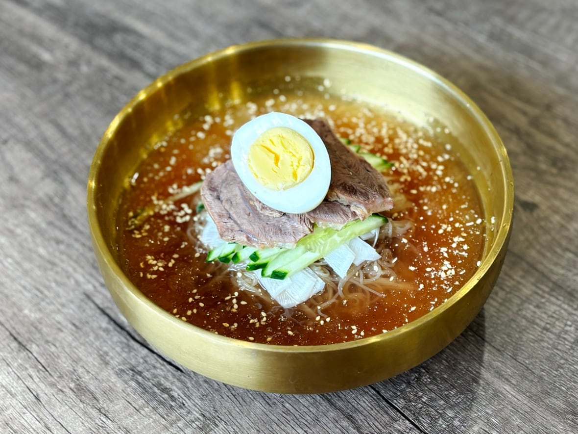 A bowl of cold noodles topped with a hard boiled egg.