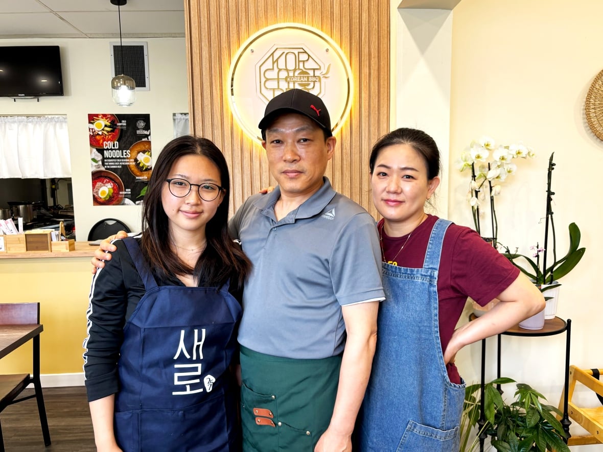 A family stand together in their restaurant.