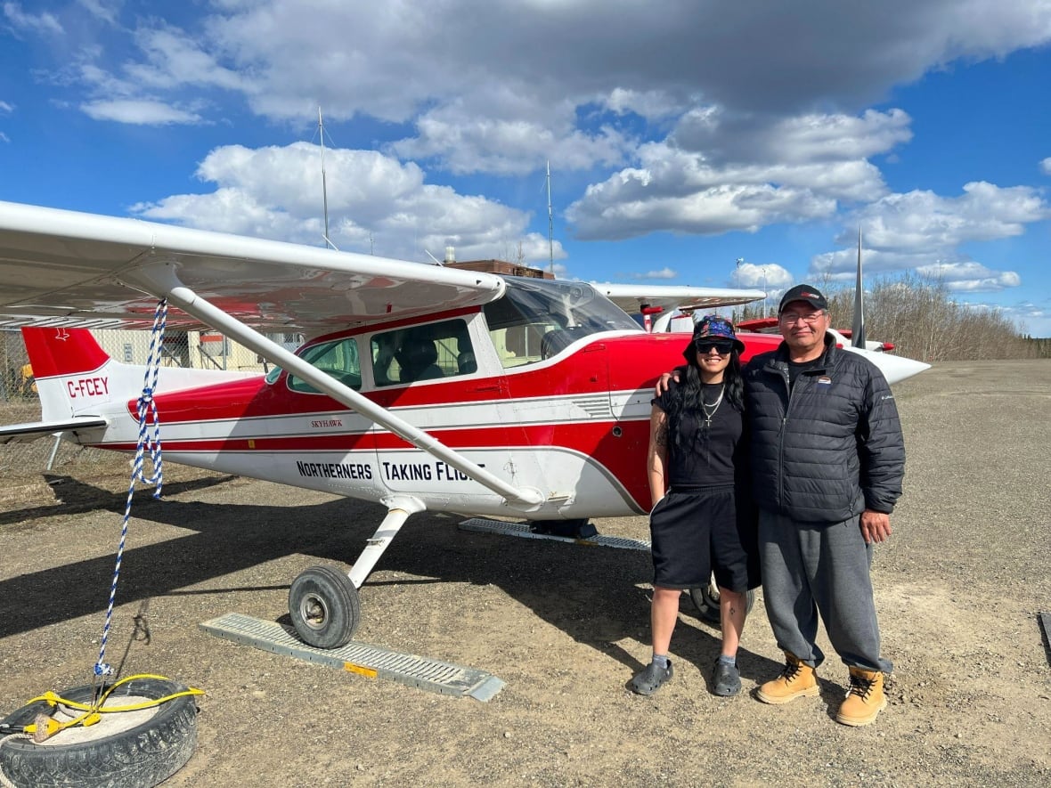 A woman and a man stand next to a small plane.