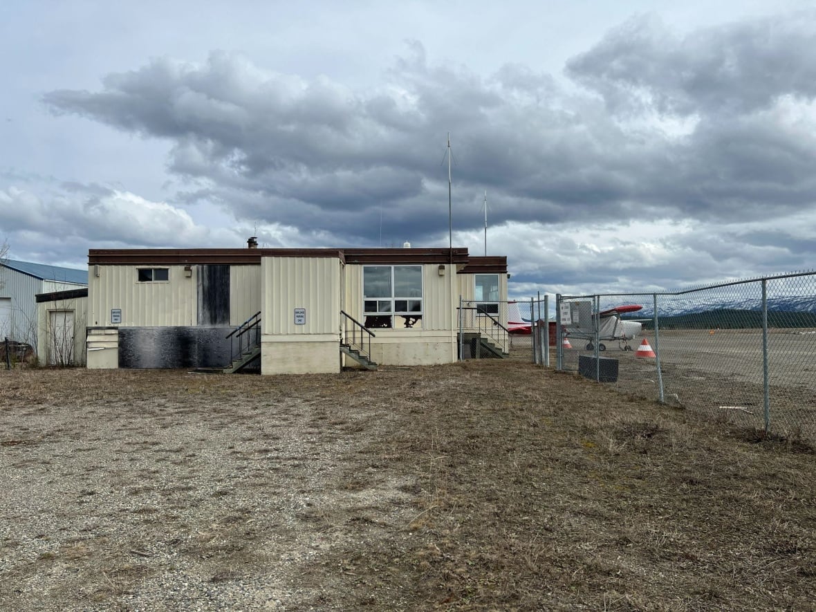 A small building with a fence and a plane. 
