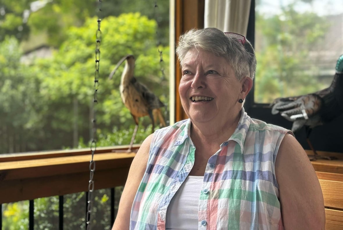 A woman on her porch looks off in the distance