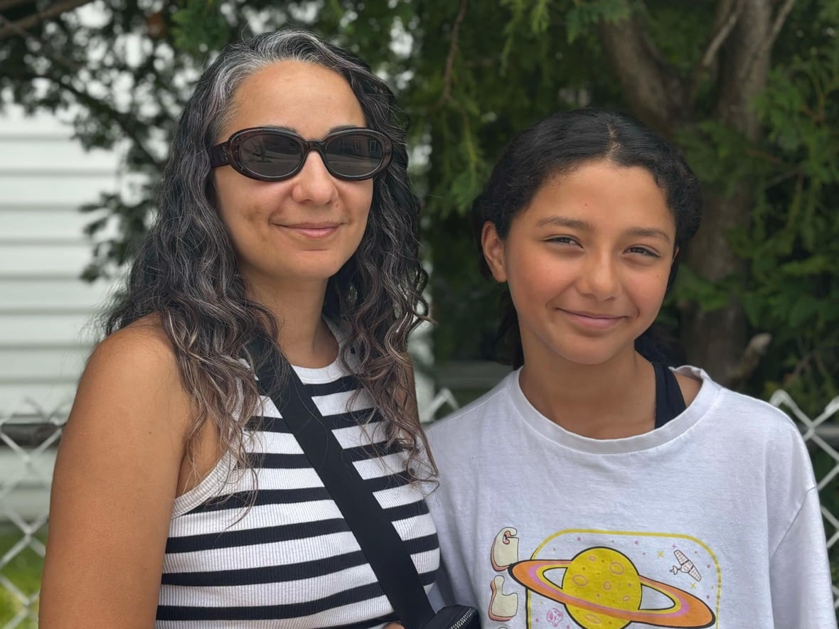 A mom and daughter smile at the camera outside