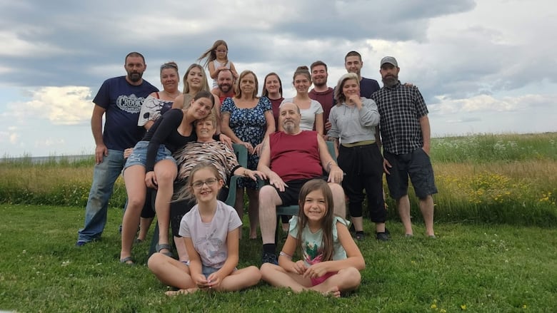  Two grand parents on chairs and other family members around them.