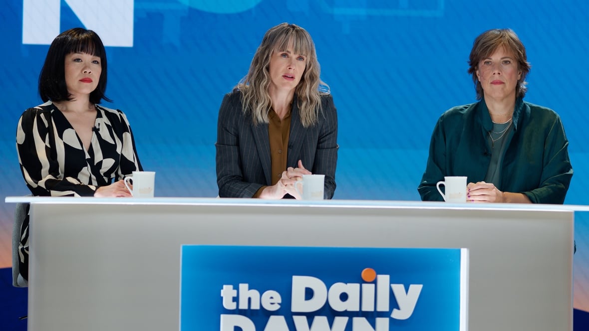 Three women sit in front of a news desk
