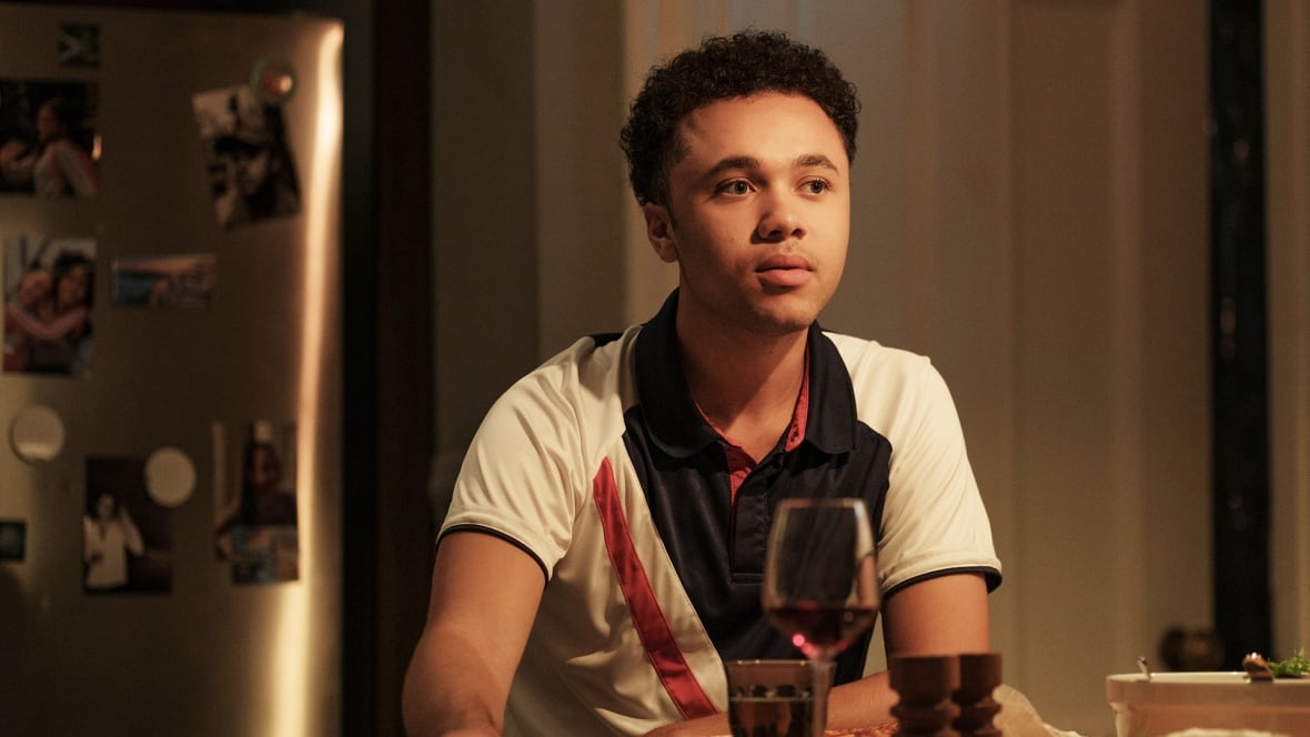 A young man sits at a dinner table.