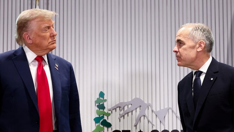 Two men in suits and ties appear in conversation as they look at one another.  