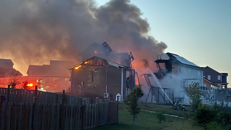 Firefighters can be seen responding to a house fire, there is a lot of smoke and the building is very damaged in the image