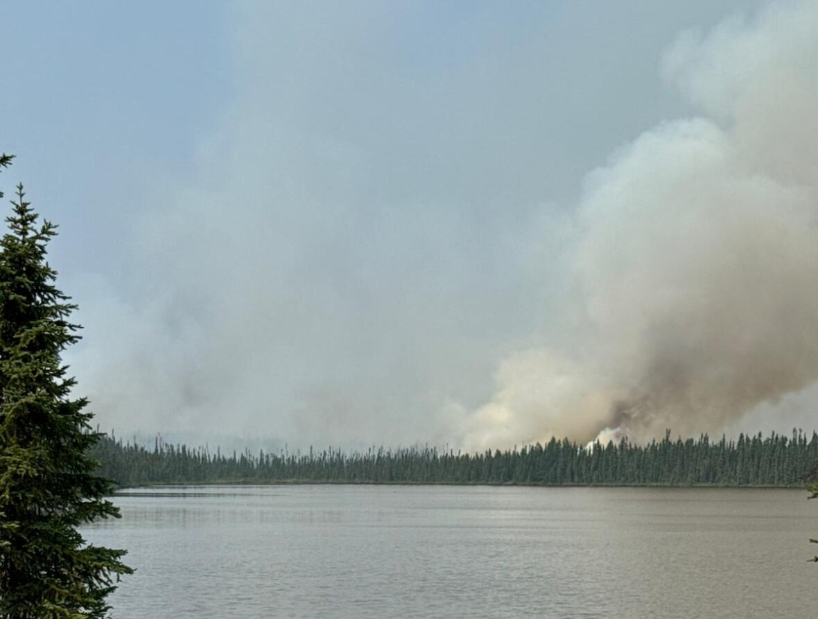 plume of grey smoke seen viewed from across a lake