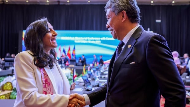 Malaysia's Foreign Minister Mohamad Hasan, right, greets Canada's Foreign Minister Anita Anand during the Association of Southeast Asian Nations (ASEAN) Post-Ministerial Conference with Canada, held as part of the 58th ASEAN Foreign Ministers' Meeting and related meetings at the Kuala Lumpur Convention Centre, Thursday, July 10, 2025. An Indian woman with black hair wearing a white suit shakes the hand of a Malaysian man with short grey hair wearing a blue suit