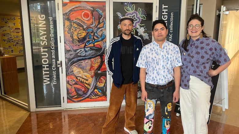 Three people stand in front of art gallery.