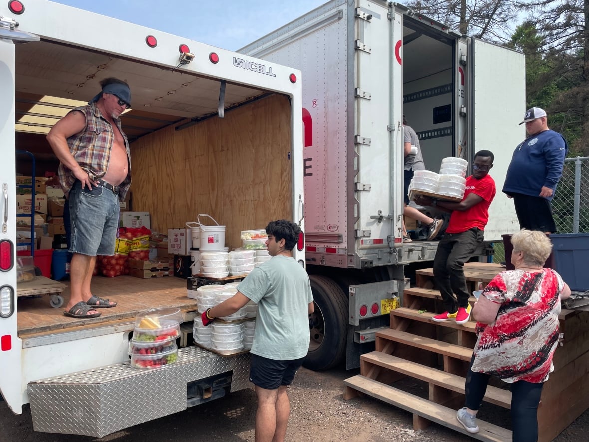 Five people can be seen behind two trucks, moving packaged food into the charities truck.