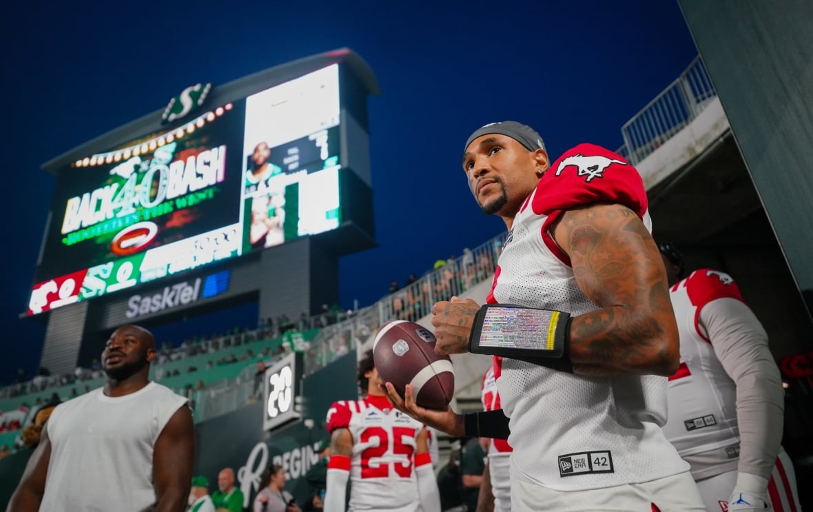 A few football players wearing white and red jerseys wait on the field before the game is supposed to start.