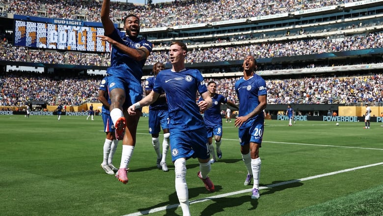 A men's soccer player celebrates a goal with teammates.