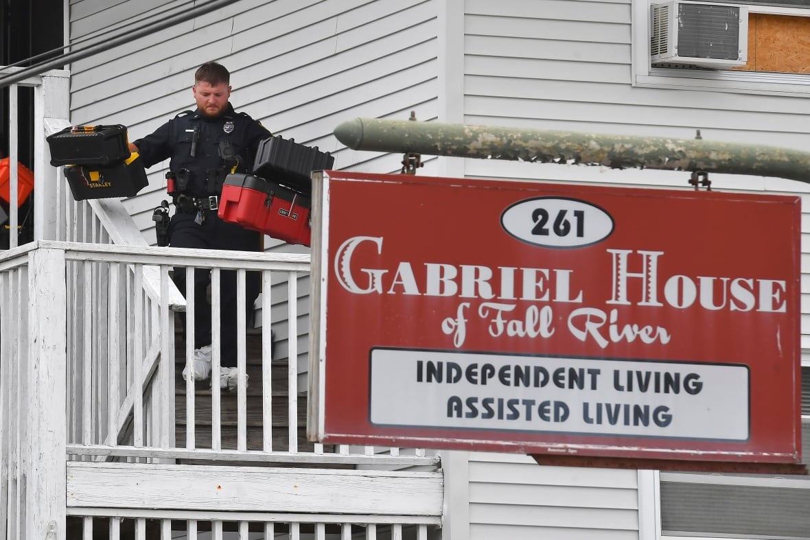 A law enforcement official removes boxes from a facility.
